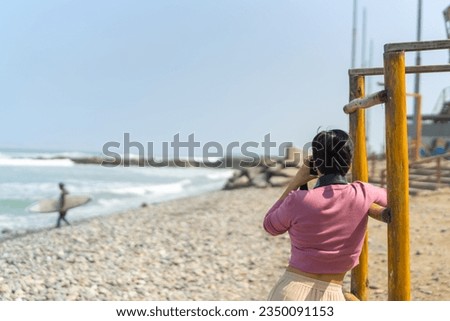 Rear view of a woman taking photos on a beach