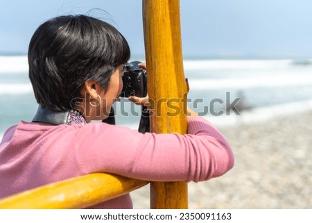 Rear view and close-up of a woman taking pictures standing on the beach