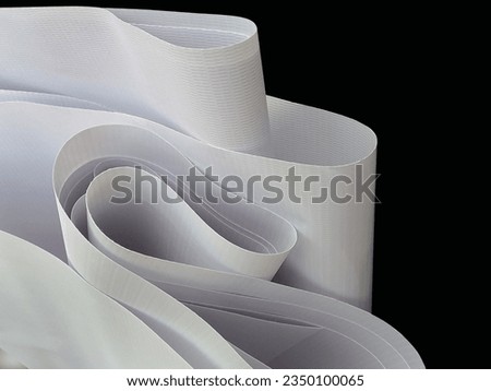 pile of plain white flexion material rolled up on dark background. flexion fabric with a fibrous texture. banner material, digital printing industry