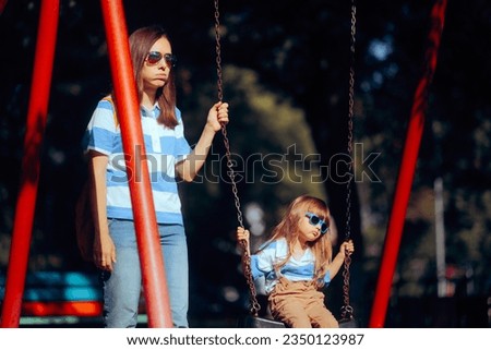 
Tired Mom and Kid Feeling Bored at the Playground. Mother and daughter not speaking after an argument 
