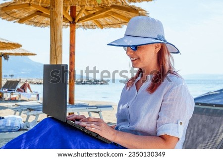 Video blogger, freelancer editing video at beach. Editing Videos On Laptop Using Video Editor App. Young woman working abroad on laptop while sitting on the beach, video editing freelance working