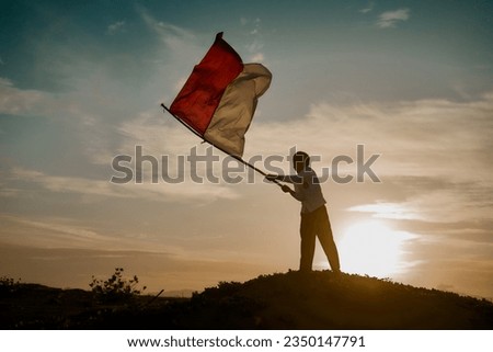Silhouette of Little Boy Waving Indonesia's Red and White Flag at Sunset