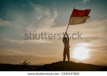 Silhouette of Little Boy Waving Indonesia's Red and White Flag at Sunset