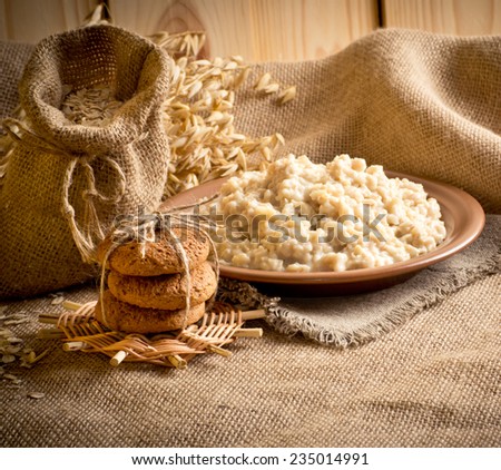 Oatmeal in the plate, oat flakes in the bag, oat cookies and spikelets on sackcloth