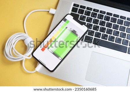 Close-up usb cable connect phone and laptop computer new technology concept on yellow background. 