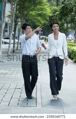 Two of Chinese business colleagues outside walking in the street
