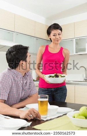 Happy young Chinese couple preparing to eating dinner at home in the kitchen