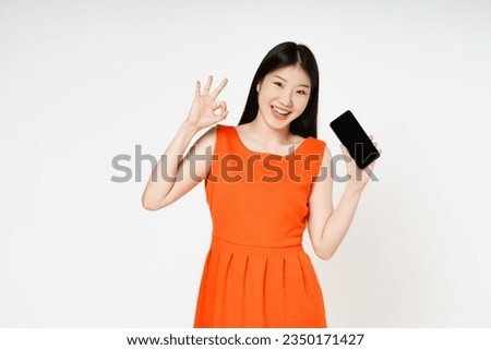 Young woman holding smartphone and shows OK sign on white background.