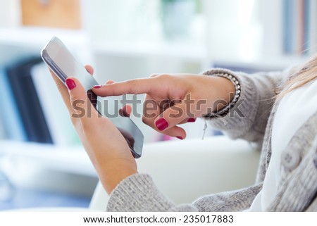 Closeup image on a female hands holding smartphone at home.