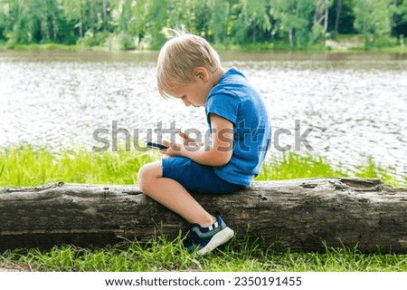 Child boy sits slouching hunched back bent,neck,looks phone,over device.incorrect unhealthy curvature position posture,body alignment.Preventing stooping scoliosis.spine problem.Dependence on gadgets. Royalty-Free Stock Photo #2350191455