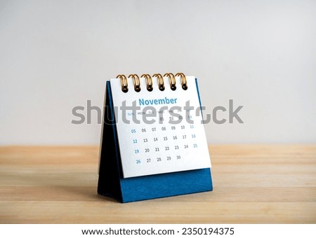 An November 2023 calendar desk for the organizer to plan and reminder isolated on wood table and white background, minimal style. Blue small table calendar with page of the 11th month.