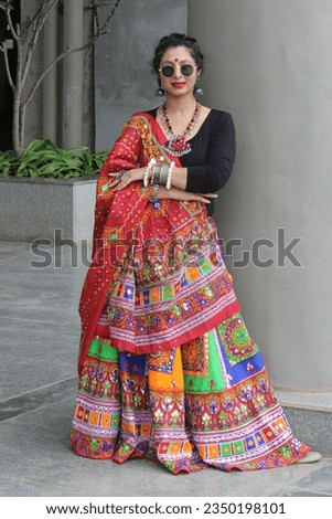 beautiful indian woman wearing red and black chaniya choli with multicolor ghaghra and fabric jewelry. Outfit for garba and dandiya in navratri festival. folk dance of gujarat india celebrated across Royalty-Free Stock Photo #2350198101