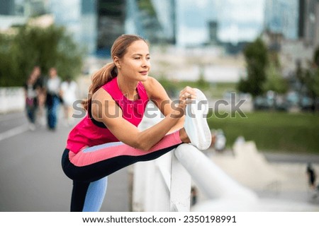 Young female runner stretching on a bridge in an urban setting