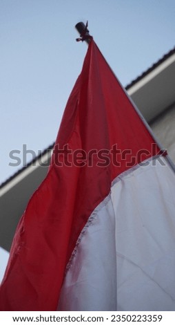 Indonesian red and white flag fluttering in the wind against a blue sky background