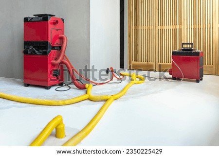 Water damage restoration service for a leaking home environment with industrial air movers, dehumidifiers and pipes to remove water and moist from the wet floor. Repair the house. Household insurance Royalty-Free Stock Photo #2350225429