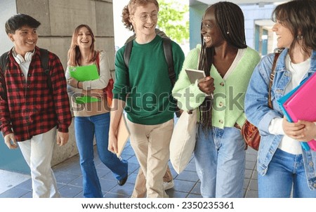 A group of high school students are walking into the school building on the first day of school. They are all smiling and look excited to start the new school year.  Royalty-Free Stock Photo #2350235361