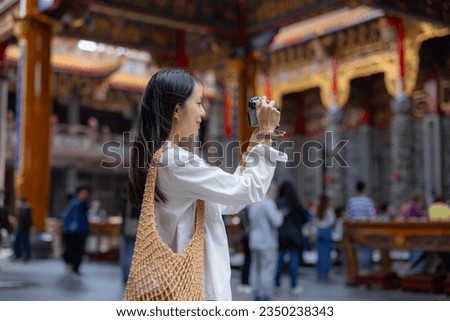 Tourist woman use digital camera to take photo in Chinese temple