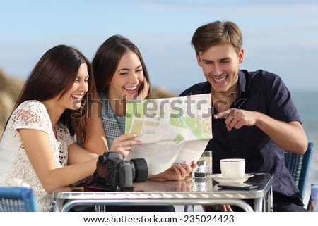 Group of young tourist friends consulting a paper map in a restaurant with the beach in the background
