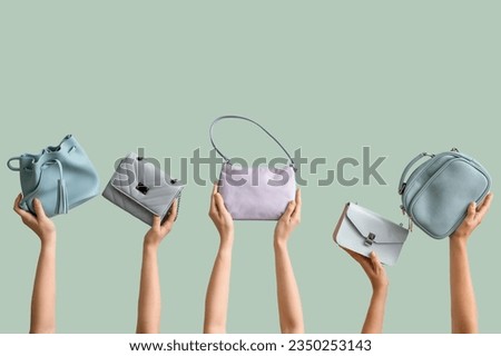 Many female hands holding different stylish bags on pale green background Royalty-Free Stock Photo #2350253143