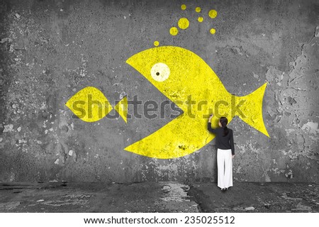 businesswoman drawing  big fish eat small fish on the wall Royalty-Free Stock Photo #235025512