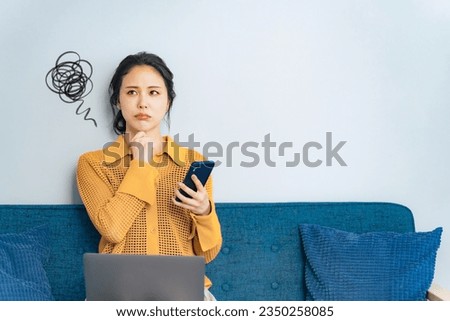 Portrait of confused young woman using a smart phone in living room. Royalty-Free Stock Photo #2350258085