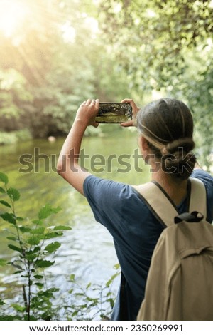 young woman taking photos on her phone, , concept of hiking and traveling, hands with camera close-up, vertical shot  