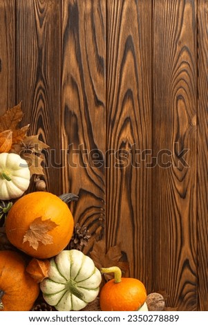 Autumn harvest showcased from above in vertical picture of ripe pumpkins and seasonal attributes arranged on a dark wooden canvas, providing copyspace for text or adverts to evoke the fall mood