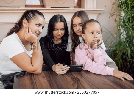 A child gets bored while adults or teenagers are busy or the concept of the effect of mobile phones on children's development, photo with selective soft focus