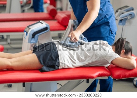 Electromagnetic therapy of the back, physiotherapist doctor uses medical equipment. Royalty-Free Stock Photo #2350283223