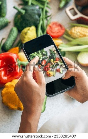 A woman takes a photo of vegetables on a smartphone.