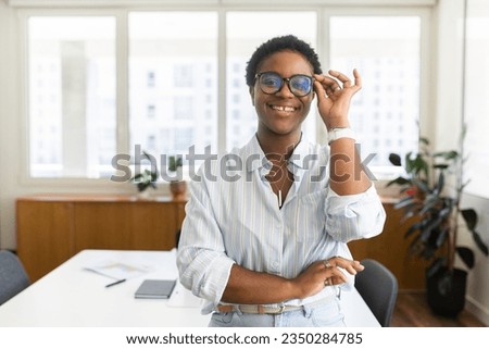 Charming charismatic african-american young businesswoman stylish eyeglasses in casual wear smiling and looking at the camera, female office employee, manager, ceo with short haircut adjusting glasses Royalty-Free Stock Photo #2350284785