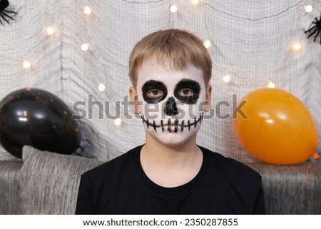 Portrait of a boy with makeup on his face in the form of skeleton for Halloween