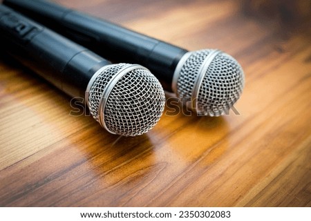 Two radio microphones lying on a wooden table surface.