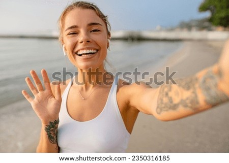 pretty young smiling woman doing sports in the morning by the sea beach in stylish sport outfit sportswear, healthy fit lifestyle, taking selfie picture on smartphone camera