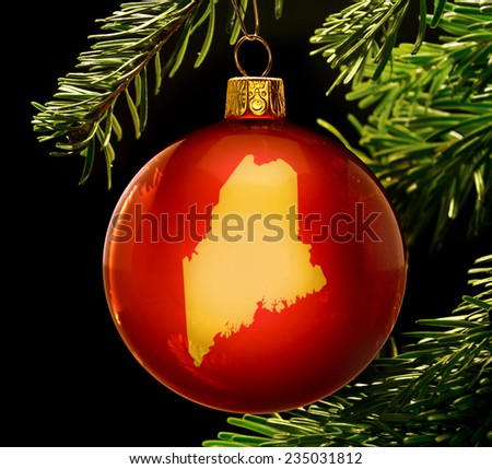 A red bauble with the golden shape of  Maine hanging on a christmas tree isolated on black.(series)