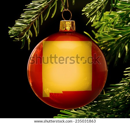 A red bauble with the golden shape of  New Mexico hanging on a christmas tree isolated on black.(series)