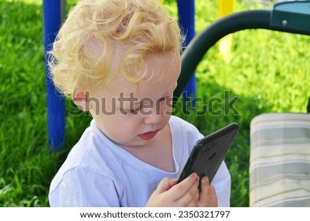 A little curly-haired boy calls on the phone