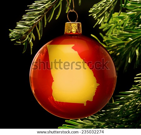 A red bauble with the golden shape of  Georgia hanging on a christmas tree isolated on black.(series)
