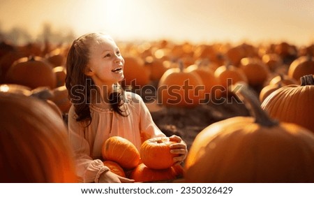 Happy child girl with orange pumpkins in the field outdoor. 