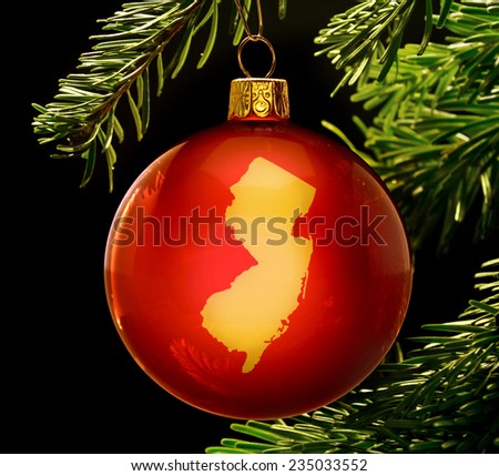 A red bauble with the golden shape of  New Jersey hanging on a christmas tree isolated on black.(series)