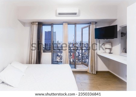 A one bedroom apartment or hotel room in Tokyo with a balcony and views of Tokyo Tower and Azabudai Hills Mori JP Tower. Minimalist design theme. Full size windows. Royalty-Free Stock Photo #2350336841