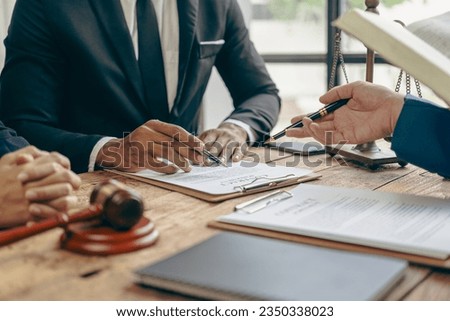 Male lawyer or judge consulting or discussing contract documents with clients Businessmen in office meeting with new clients sharing legal advice explaining legal process Royalty-Free Stock Photo #2350338023