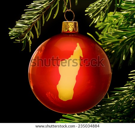 A red bauble with the golden shape of  Madagascar hanging on a christmas tree isolated on black.(series)