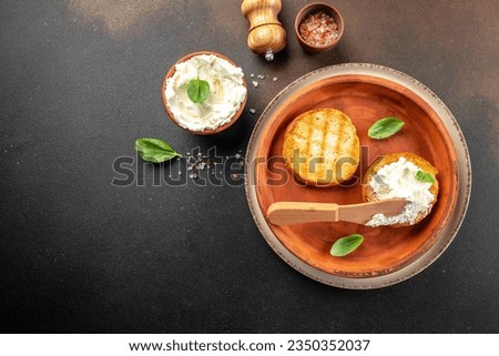 toasted bread with cream cheese and fresh basil leaves on a dark background. banner, menu, recipe place for text, top view. Royalty-Free Stock Photo #2350352037