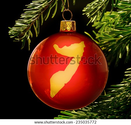 A red bauble with the golden shape of  Somalia hanging on a christmas tree isolated on black.(series)