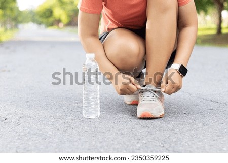 Runner woman tying Running shoes laces for preparing for a run a jog outside. Jogging girl exercise motivation heatlh and fitness. Active asian runner woman tying shoe lace before running.