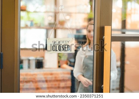 Woman staff turning close sign board on glass door in coffee shop and cafe restaurant during lockdown quarantine, Business overtime concept, Close up shot of window sign