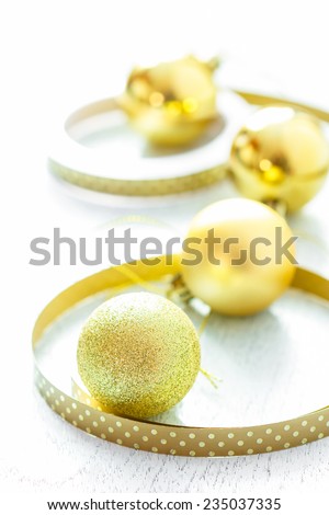 Gold Christmas balls with ribbon on wooden background.