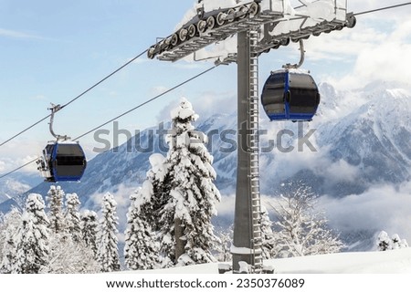 New modern spacious big cabin ski lift gondola against snowcapped forest tree and mountain peaks covered in snow landscape in luxury winter alpine resort. Winter leisure sports, recreation and travel Royalty-Free Stock Photo #2350376089