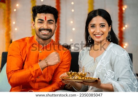 Happy smiling indian brother showing rakhi with sister by looking at camera at home - concept of family relationship, tradition ceremony and indian culture. Royalty-Free Stock Photo #2350385047